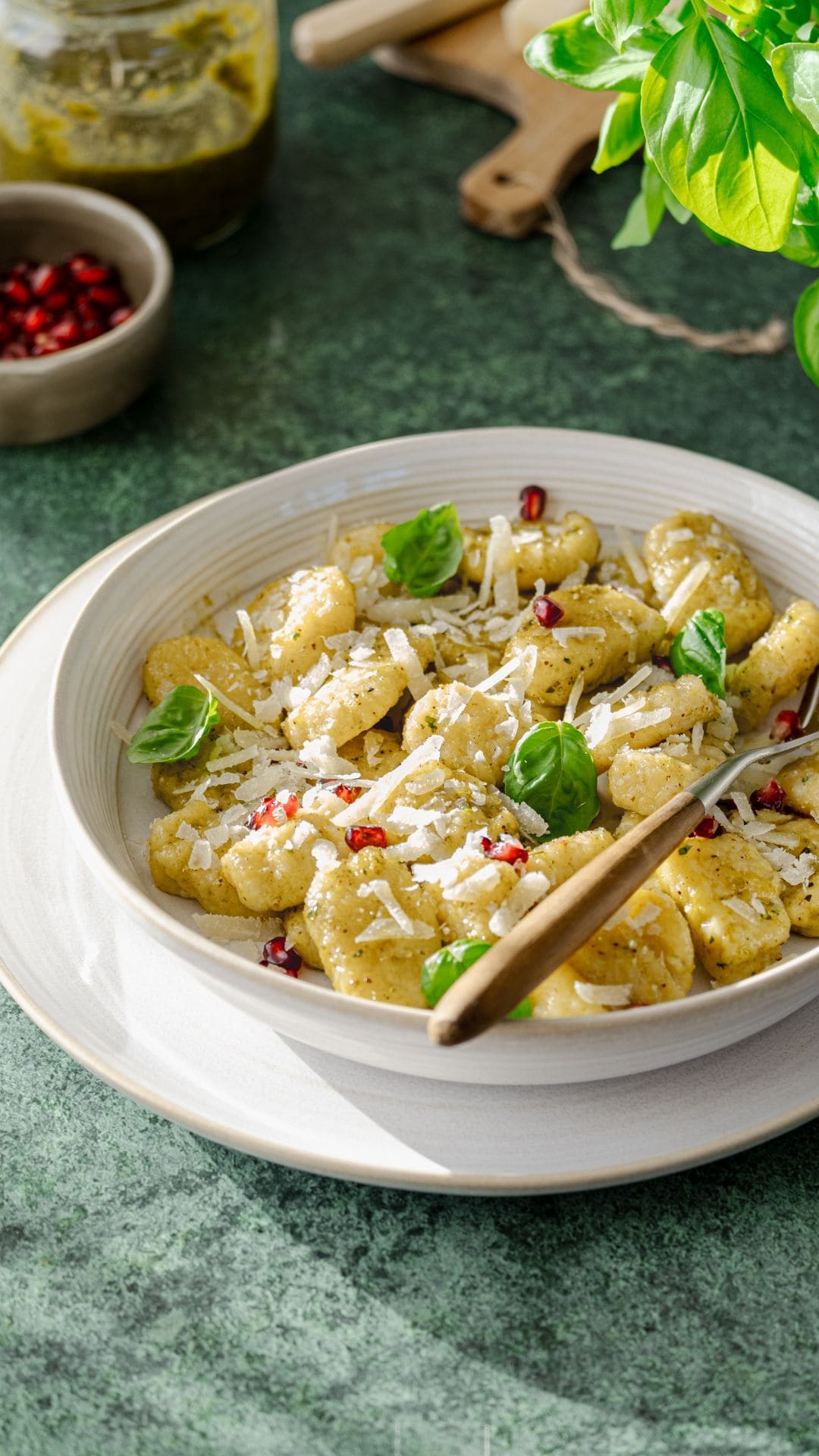 Sellerie-Gnocchi im Teller mit geriebenem Parmesan, Granatapfelkernen und Basilikumblätter